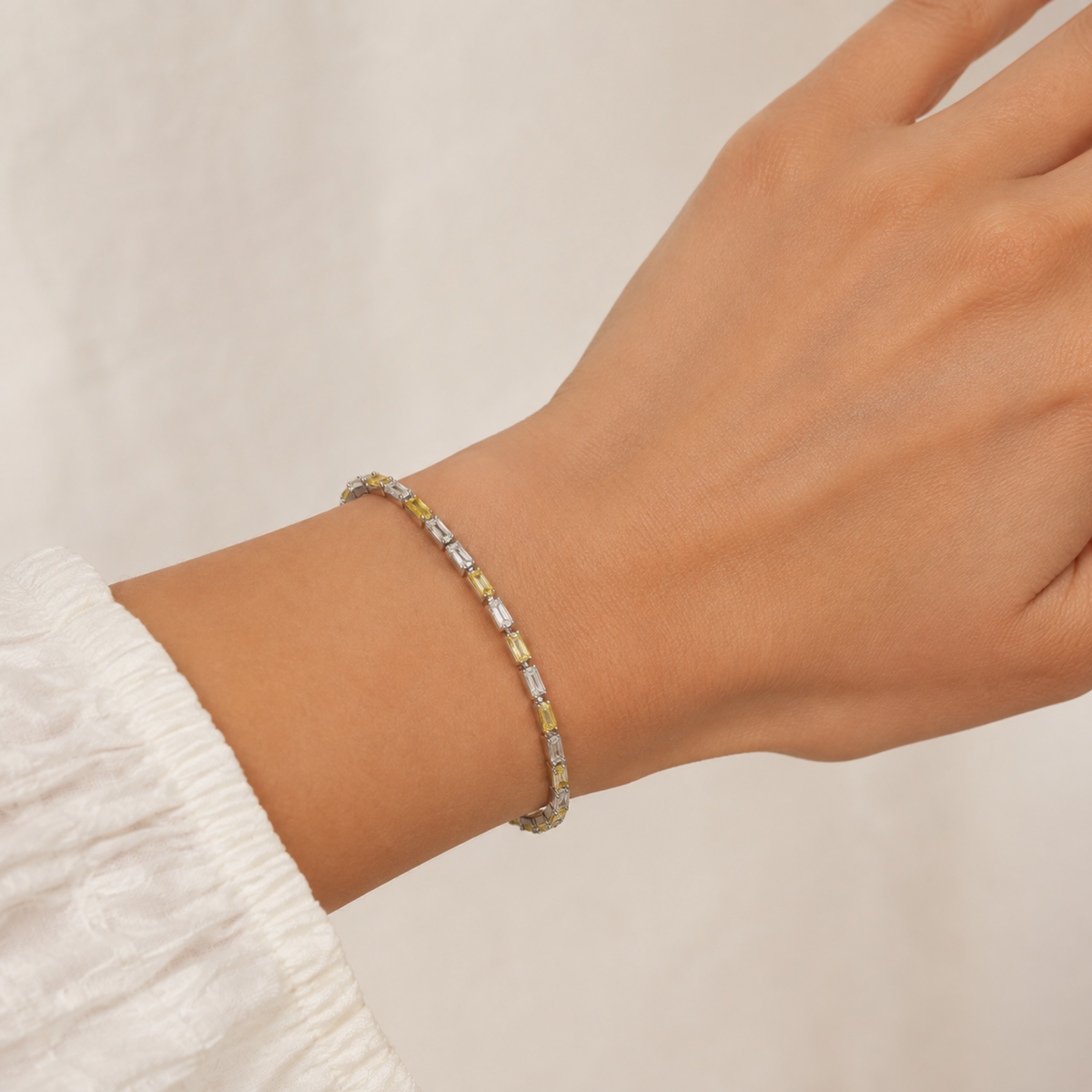 Kadın bileğinde Marevia Gold sarı ve şeffaf baget zirkon taşlı gümüş bileklik
